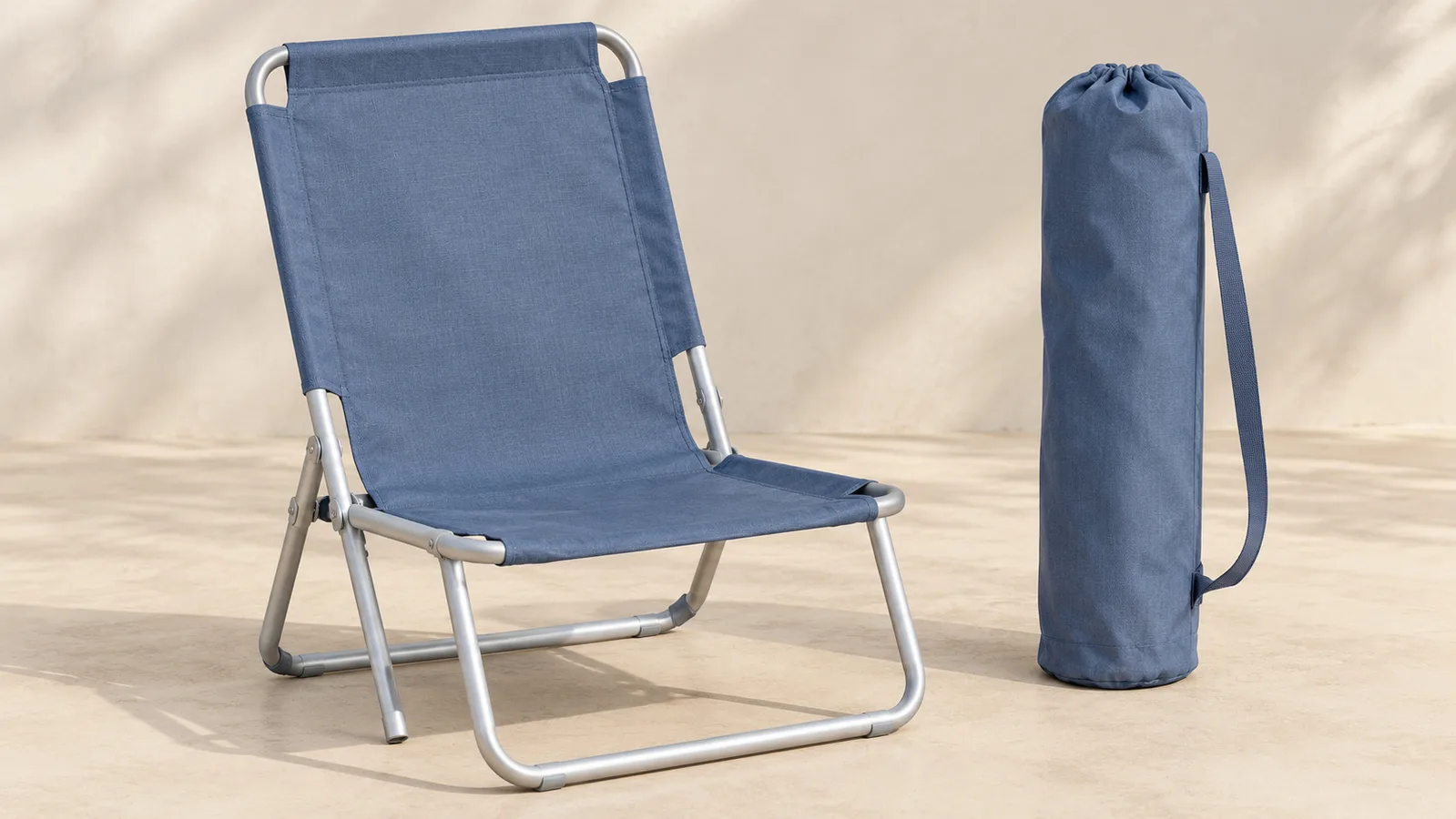 Une chaise de plage pliante simple présentée ouverte à côté de son sac de transport assorti
